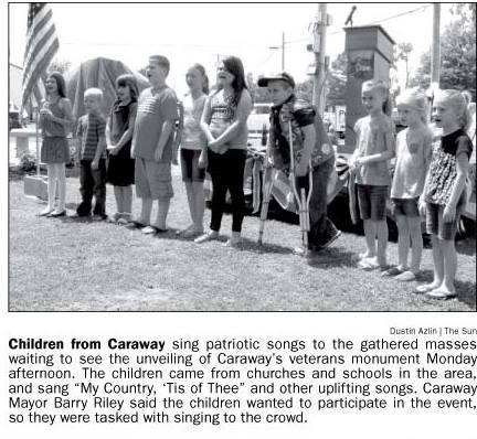 Newspaper snippet: Children from Caraway sing patriotic songs during the unveiling of the Veterans Monument